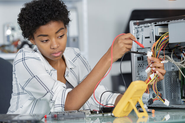 Eine junge Frau misst elektrische Größen mit einem Multimeter.
